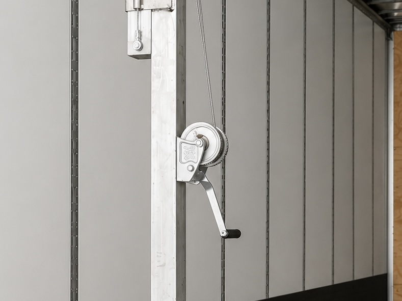 Close-up of the TRSS hand-crank winch mounted on the aluminum post inside a trailer